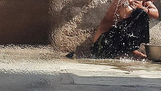 Indian sister-in-law is bathing in the open courtyard of the house, putting a finger in her burrow and rubbing the body, sister-in-law is washing the bathroom.