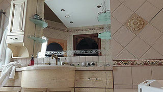A Charming Woman Is Preening in the Bathroom in Front of a Mirror