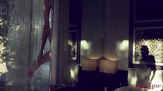 Katya Clover squats under showerhead on green tiled stall floor