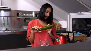 A cute girl peels a cucumber for her older man in a sensual scene.
