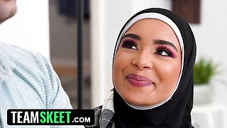 Woman in black hijab and plaid shirt talks on navy couch