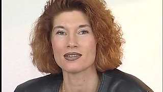 Tattooed ginger milf is filling her pussy with a big dildo